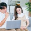 パソコンを見て悩む妊婦